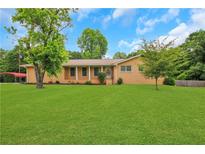 Charming brick home with a well-manicured lawn and mature trees, creating a welcoming curb appeal at 3332 Oak Grove Rd, Loganville, GA 30052