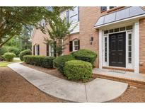 Brick home featuring a welcoming front entrance, meticulously maintained shrubbery and a sidewalk through the yard at 11100 Chandon Way, Johns Creek, GA 30097