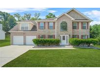 Charming two-story brick home featuring a manicured lawn, red shutters, and a two-car garage at 6799 Hill Creek Cv, Lithonia, GA 30058