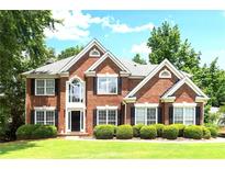 Stunning two-story red brick home featuring manicured lawn and lush landscaping at 194 Lake Ruby Dr, Suwanee, GA 30024