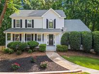 Charming two-story home boasts a well-manicured lawn, lush landscaping, and a welcoming front porch with black shutters at 6065 Ashbury Ln, Cumming, GA 30028