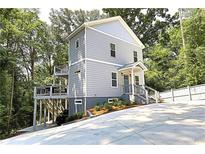 Charming three-story home with modern siding, front porch, and deck surrounded by lush greenery at 2125 Clay Rd, Austell, GA 30106
