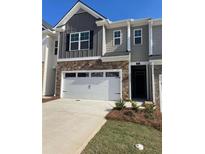 Charming townhome showcasing a two-car garage, stone accents, and neutral gray siding at 1404 Gray Branch Dr, Lawrenceville, GA 30045