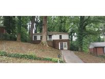 Two-story home with brick and siding exterior and a long driveway surrounded by mature trees at 2980 Wanda Sw Cir, Atlanta, GA 30315