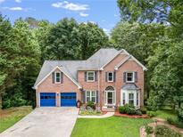 Charming two-story brick home with blue garage doors, lush lawn, and mature trees at 41 Wexford Nw Cir, Cartersville, GA 30121