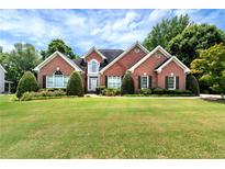 Charming brick home boasts a manicured lawn, lush landscaping, and classic architectural details at 3885 Lake Juliette Dr, Buford, GA 30519