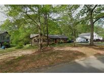 Charming one-story home featuring brick facade, red shutters and mature trees in a leafy green neighborhood at 165 Wellington Dr, Mcdonough, GA 30252