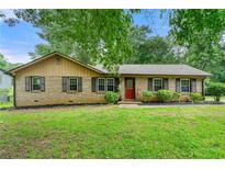 Charming brick home featuring a well-maintained lawn, trimmed shrubbery, and black shuttered windows at 165 Wellington Dr, Mcdonough, GA 30252