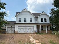 New two-story home with white siding, covered porch, three-car garage, and professionally landscaped yard at 344 Riverwood Pass, Dallas, GA 30157