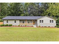 Charming ranch-style home with a manicured lawn, stone accents, and a cozy front porch, perfect for suburban living at 6142 Hutchins Dr, Buford, GA 30518