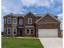 Two-story brick home featuring an attached two-car garage and a well-manicured front lawn at 365 Rodeo Dr, Auburn, GA 30011