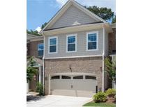 Charming townhouse featuring a two-car garage, brick accents, and lovely curb appeal with landscaped yard at 203 Holden Way, Woodstock, GA 30189