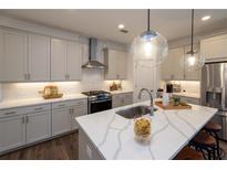 Stylish kitchen features an island with seating, grey cabinets, and stainless steel appliances at 1003 Crown Oak St # 43, Johns Creek, GA 30022