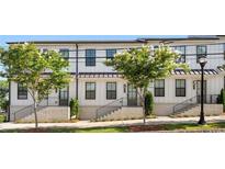 Charming townhome showcases clean white facade, contrasted by modern black window frames and updated landscaping at 988 Viney Nw Way, Atlanta, GA 30318