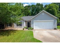 Charming single-story home featuring gray siding, stone accents, manicured lawn, and attached two-car garage at 784 Crestworth Xing, Powder Springs, GA 30127