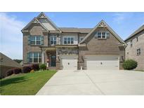 Beautiful brick two-story home with a manicured lawn and a two-car garage at 4154 Hawking Dr, Suwanee, GA 30024