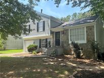 Charming two-story home with stone facade and landscaped front yard and classic black shutters at 4164 River Shoals Ct, Duluth, GA 30097