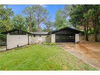 Charming ranch-style home with a well-manicured lawn, white brick, a black roof, and a two-car garage at 3068 Cherry Blossom Ln, Atlanta, GA 30344