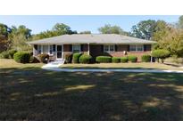Charming brick home featuring a well-manicured lawn and mature landscaping with decorative bushes at 893 Andrews Dr, Conyers, GA 30012