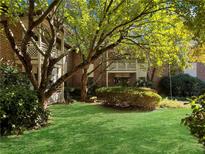 View of the building exterior with lush lawn and mature shade trees in a well-maintained community at 475 Mount Vernon Ne Hwy # C229, Atlanta, GA 30328