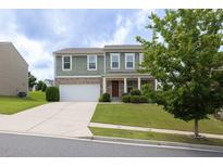 Inviting two-story home featuring manicured lawn, attached two-car garage, and covered front porch at 1530 Avalon Creek Rd, Sugar Hill, GA 30518