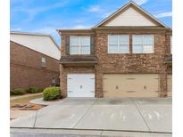 Stone-clad townhouse exterior featuring a two-car garage and meticulously maintained landscaping at 805 Pleasant Hill Nw Rd # 231, Lilburn, GA 30047