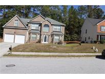 Two story brick home featuring a two car garage and manicured lawn at 1962 Bridgestone Cir, Conyers, GA 30012