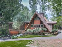 A-frame home nestled in a wooded area with a garage, brick accents, and well-manicured landscaping at 1467 Shiloh Trail East Nw, Kennesaw, GA 30144