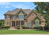 Charming two-story home showcasing a blend of stone and green siding, manicured lawn, and lush landscaping at 3820 Preserve Crossing Ln, Cumming, GA 30040