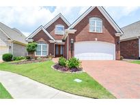 Charming brick home featuring a manicured lawn and a brick driveway leading to a two-car garage at 1570 Woodberry Run Dr, Snellville, GA 30078