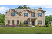 Traditional two-story brick home with a well-manicured lawn and mature landscaping at 361 Traditions Ln, Hampton, GA 30228