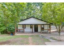 Charming cottage-style home with a cozy front porch and a well-maintained lawn surrounded by lush trees at 2155 Cove Trl, Cumming, GA 30041