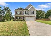 Charming two-story home with stone accents, a well-manicured lawn, and a welcoming two-car garage at 140 Canyons Ct, Hampton, GA 30228