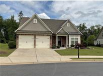 Charming home features a two-car garage, brick accents, and well-maintained landscaping at 1790 Nestledown Dr, Cumming, GA 30040