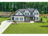 Beautiful two-story home with landscaped yard, white brick, black shutters and an attached two-car garage at 411 Oakleigh Ave, Woodstock, GA 30188