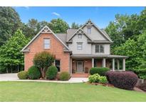 Charming two-story home with a brick and gray shingle exterior, complemented by a lush, well-manicured front yard at 7535 Antique Barn Ave, Cumming, GA 30041