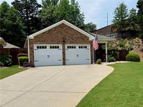 Charming brick home featuring a two-car garage and an American flag, complemented by a well-manicured lawn at 112 Countryside Ct, Woodstock, GA 30189