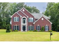 Charming brick home with manicured lawn, mature trees, and classic architectural details at 6625 Eagle Pt, Suwanee, GA 30024