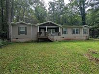 Charming single-story home with a inviting front porch, complemented by a large front yard surrounded by mature trees at 512 S Holly Springs Rd, Woodstock, GA 30188