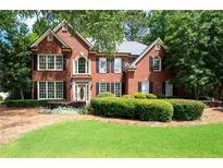 Charming brick home featuring manicured landscaping and a welcoming front lawn at 1558 Amberwood Creek Nw Dr, Kennesaw, GA 30152