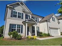 Charming two-story home featuring a white brick facade, black shutters, covered entryway, and an attached two-car garage at 3332 Grace Farm Ln, Buford, GA 30519
