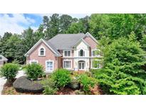 Charming two-story brick home featuring a manicured lawn, mature trees, and a welcoming double-door entrance at 12130 Helleri Holw, Alpharetta, GA 30005