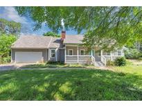 Charming single-story home with a covered porch, attached garage, and well-maintained lawn at 6744 Rockbridge Rd, Stone Mountain, GA 30087