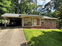 Charming brick home with carport, inviting front porch, and well-manicured lawn at 2543 Asbury Court Ct, Decatur, GA 30033