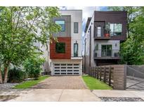 Modern, three-story home featuring a brick driveway, a two-car garage, and a mix of white, wood, and gray exterior accents at 167 Sampson Ne St, Atlanta, GA 30312