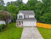 Charming two-story home with a well-maintained lawn and a two-car garage nestled among green trees at 2732 Dahlonega Trl, Austell, GA 30106