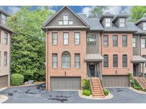 Elegant brick townhome showcasing a private entrance, attached garage, and professionally landscaped front at 4222 Rickenbacker Ne Dr # 9, Atlanta, GA 30342