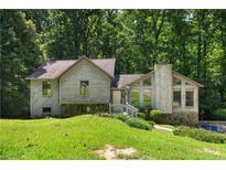 Charming two-story home with unique architectural details and a lush green lawn surrounded by mature trees at 3323 Silver Ridge Ct, Duluth, GA 30096