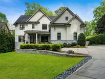 Stunning two-story white home featuring a well manicured lawn and stone retaining wall adding to the curb appeal at 4225 Wieuca Ne Rd, Atlanta, GA 30342