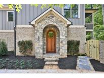 Charming stone archway frames the wooden front door, set in a landscaped front yard at 2179 William Way, Atlanta, GA 30345